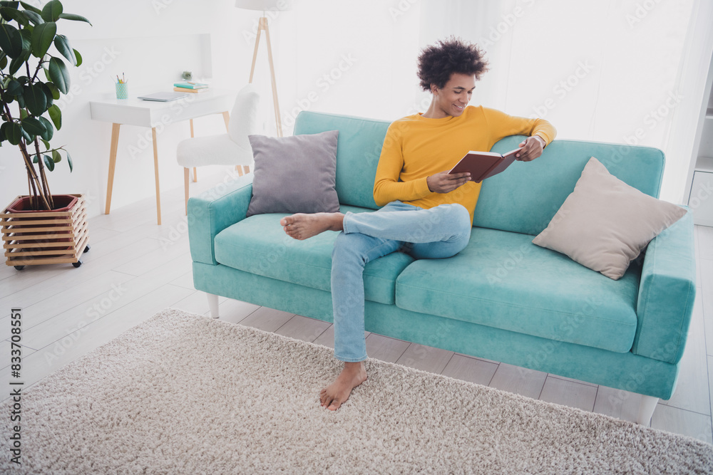 Full length portrait of nice young man read book wear pullover white interior flat indoors Full length portrait of nice young man read book wear pullover white interior flat indoors