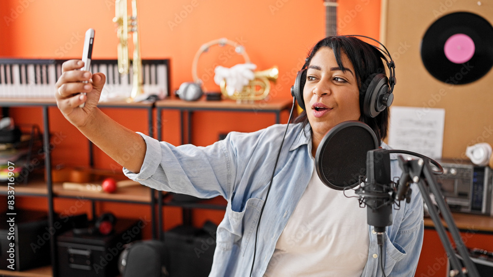 A cheerful woman takes a selfie while recording in a vibrant music studio with professional equipment A cheerful woman takes a selfie while recording in a vibrant music studio with professional equipment