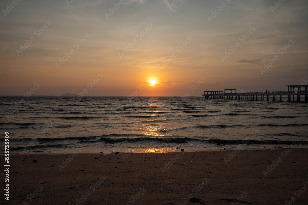 A Serene Sunset Over the Ocean With a Distant Pier and a Silhouetted Horizon
