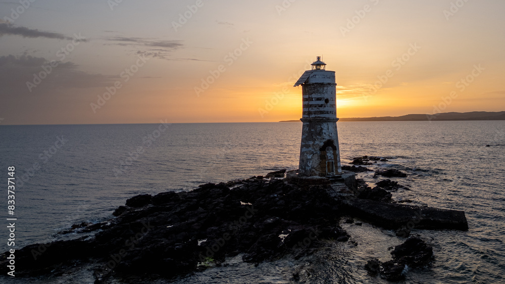 Lighthouse surrounded on the sea at sunset