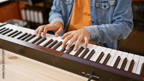 Hispanic man playing piano indoors at a music studio, showcasing his musical talent in a casual setting.