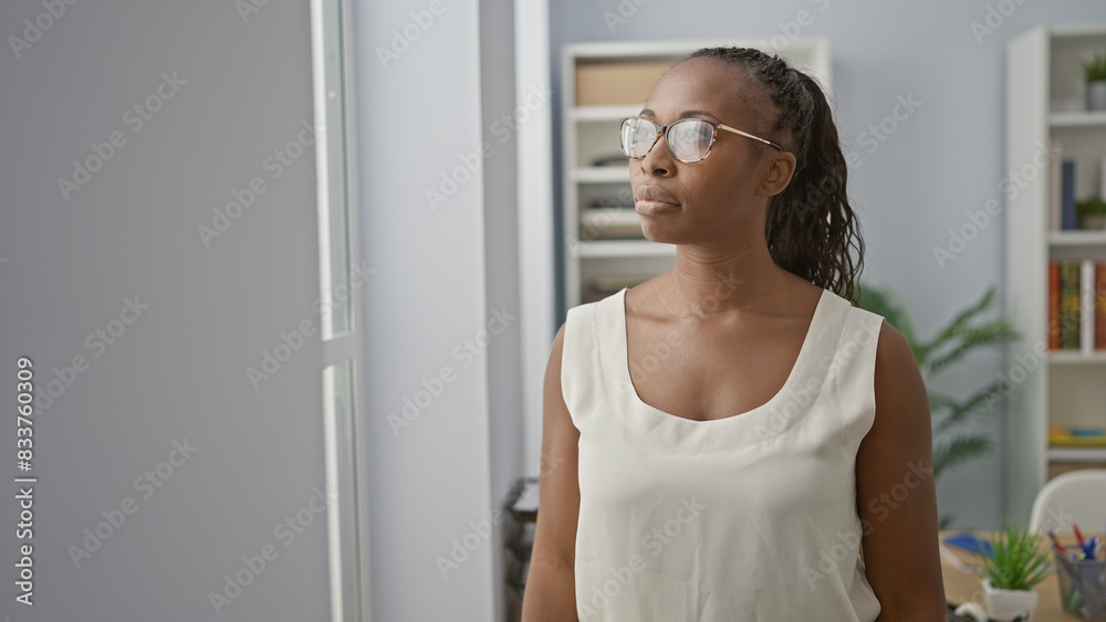 Young adult woman with glasses and curly hair deep in thought at the workplace. Young adult woman with glasses and curly hair deep in thought at the workplace.
