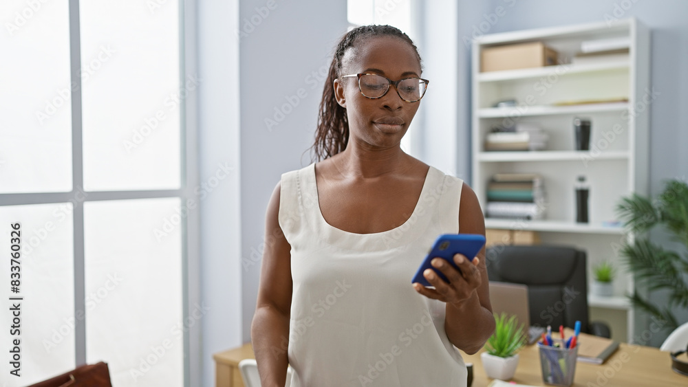 Professional african woman using smartphone in modern office interior