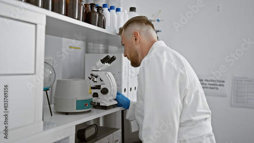 A focused caucasian man with a beard works meticulously in a laboratory setting.