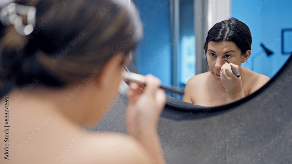 Young beautiful hispanic woman applying make up in the bathroom Young beautiful hispanic woman applying make up in the bathroom