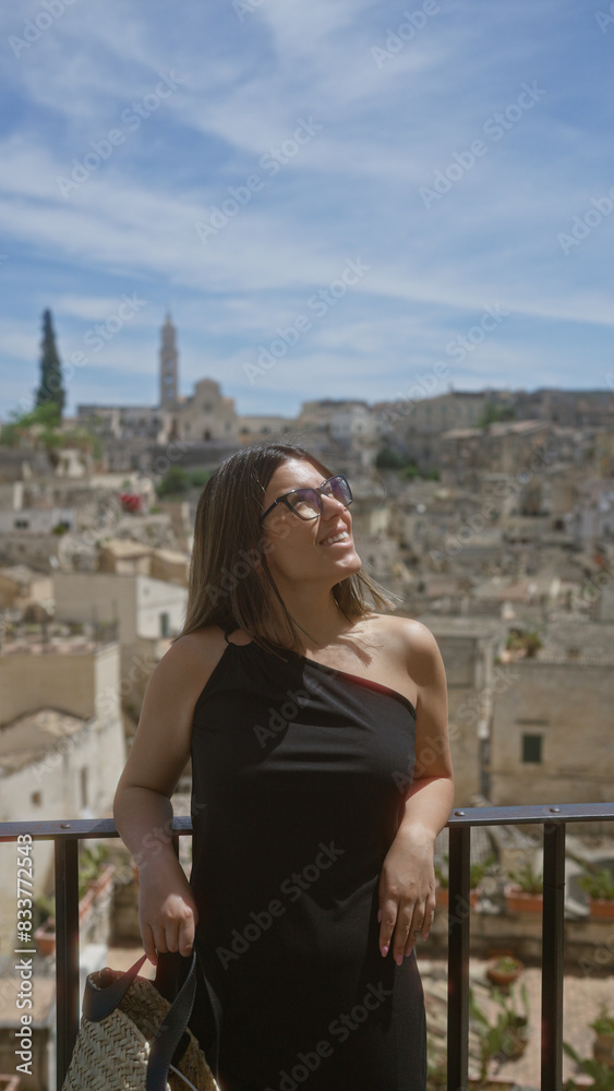 A beautiful young hispanic woman enjoying a sunny day at a viewpoint in the old town of matera, basilicata, italy, with historic buildings and a clear blue sky as the backdrop. A beautiful young hispanic woman enjoying a sunny day at a viewpoint in the old town of matera, basilicata, italy, with historic buildings and a clear blue sky as the backdrop.