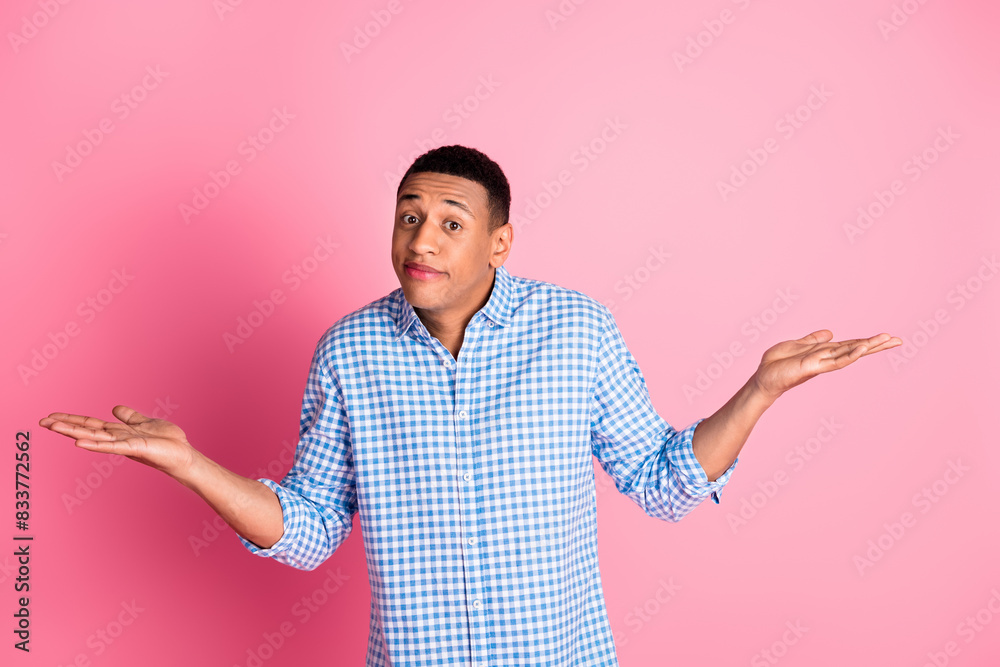 Photo of doubtful funny guy wear plaid shirt comparing arms emtpy space isolated pink color background Photo of doubtful funny guy wear plaid shirt comparing arms emtpy space isolated pink color background