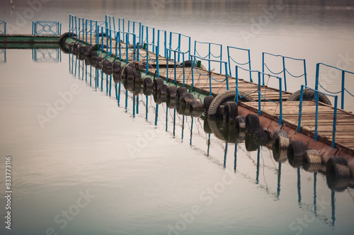 Wooden pier on the lake at daylight. Long dock for boats on the beach.