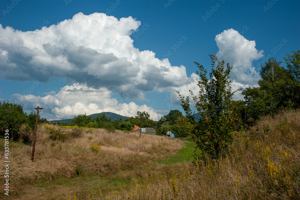 Summer landscape in a mountain village with green mountains and white clouds against a blue sky Summer landscape in a mountain village with green mountains and white clouds against a blue sky