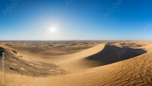 A panoramic view of a desert landscape with sand dunes and a clear blue sky. AI generated