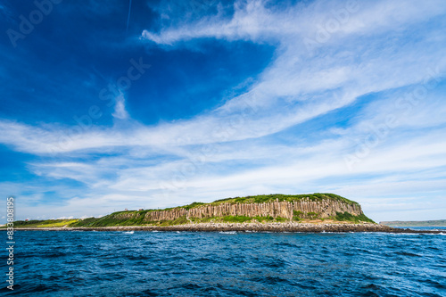Beautiful view of Tongpan Island with a blue sky background in Penghu, Taiwan. The island is a basalt mesa landform with a shoreline of cliffs made of basalt columns.