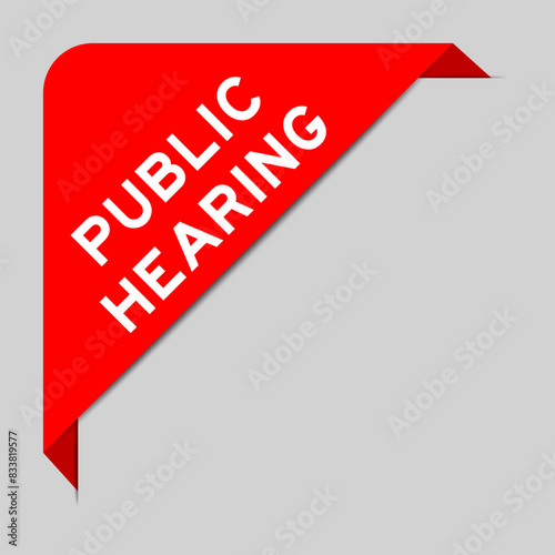 Red color of corner label banner with word public hearing on gray background