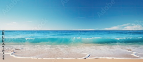 Ocean waves lapping the shore under a clear blue sky, with ample copy space image.