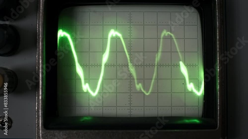 A vintage oscilloscope shows a steady green signal waveform on its screen, capturing the essence of retro technology and scientific instrumentation. photo