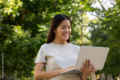Connected with technology and nature: young woman in the park with her laptop