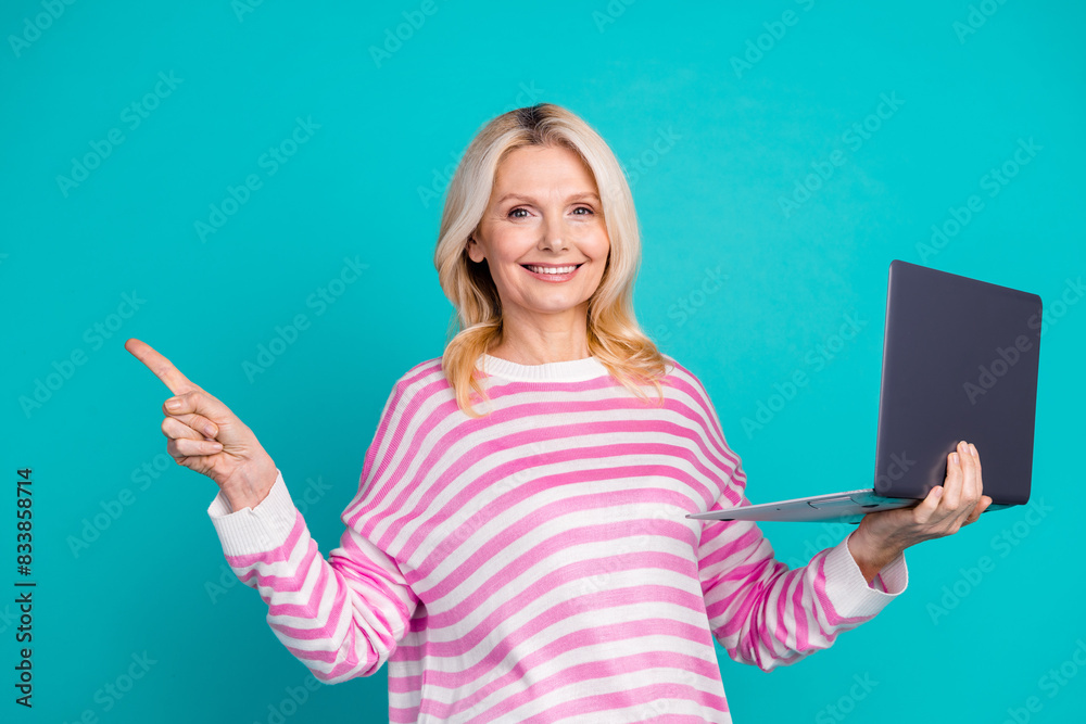 Photo of clever woman with blond hair wear striped sweatshirt holding laptop indicating empty space isolated on blue color background Photo of clever woman with blond hair wear striped sweatshirt holding laptop indicating empty space isolated on blue color background
