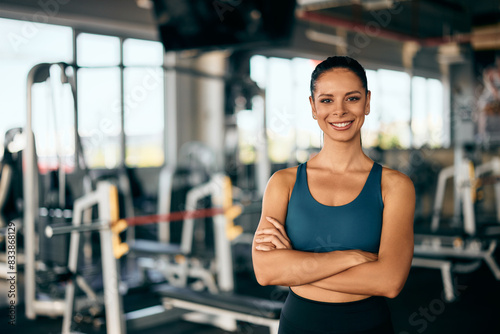 Portrait of a fitness girl, holding her hands crossed, smiling for the camera. © bnenin