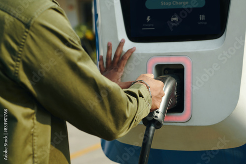 Cropped image of ev owner taking plug from public charging station