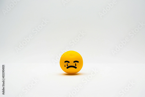 A minimalist composition featuring the solitary yellow crying emoji against a backdrop of pristine white.