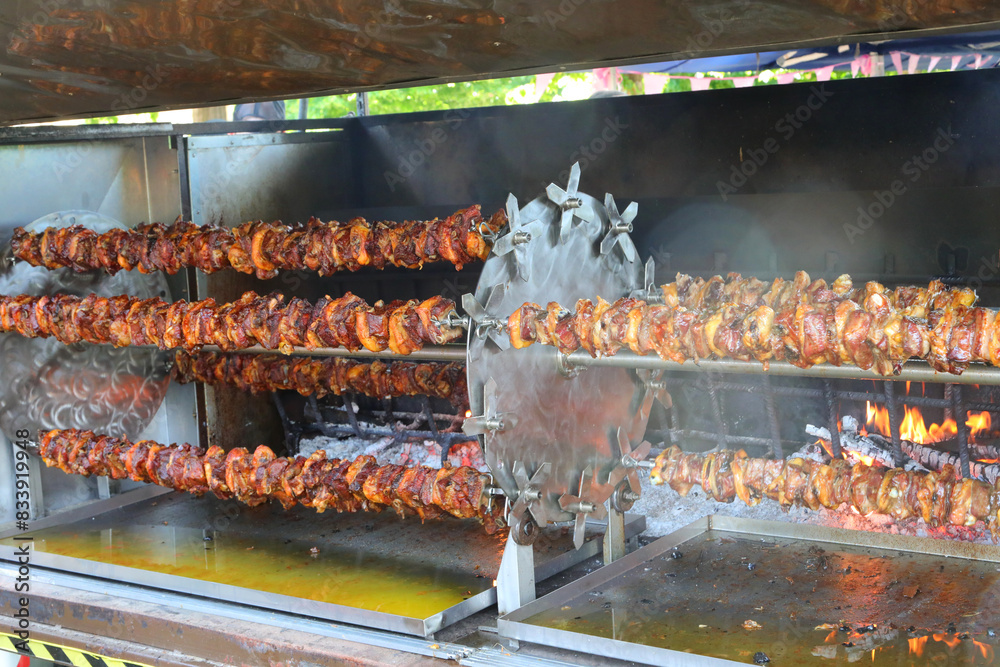 multitude of spit-roasted chickens cooked on a very big rotisserie