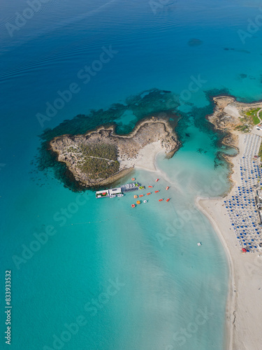 Obraz na płótnie Nissi beach with Nissi island in the morning. High altitude aerial vertical view. Calm sea on a sunny morning with no people in Ayia Napa, Cyprus. Turquoise and deep blue Mediterranean sea. w salonie