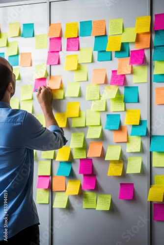 Woman organizer attaches colorful sticky notes to white board. Life hack for easy memorization and reminders of important things in visible place in office. Organization of space and clear schedule.