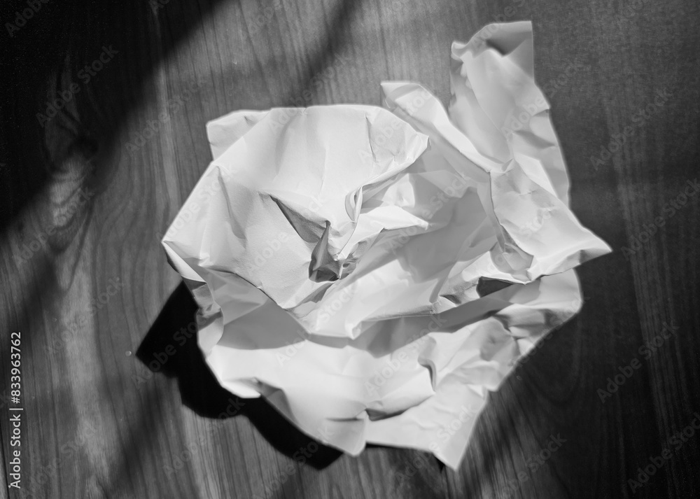 Crumpled white sheet of paper on rustic wooden surface, selective focus. Crumpled white sheet of paper on rustic wooden surface, selective focus.