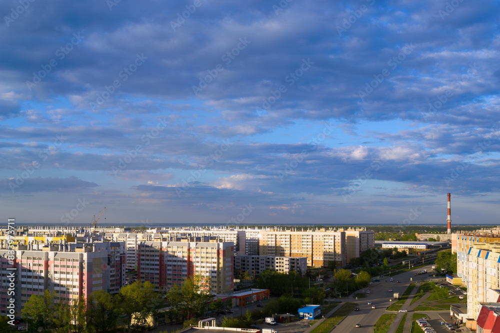 Fototapeta premium Top view of the city in the light of the sun under a cloudy sky at sunset