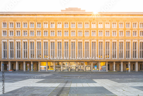 Photography Sunlight flares above the historic Tempelhof Airport terminal in Berlin, casting a warm glow on its facade