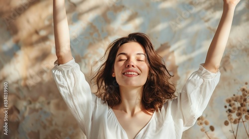 Joyful Woman Stretching with Arms Raised in a Sunlit Room photo