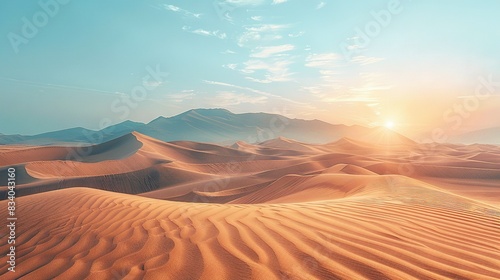   A desert landscape is captured at sunset  featuring sand dunes in the foreground and a distant mountain range