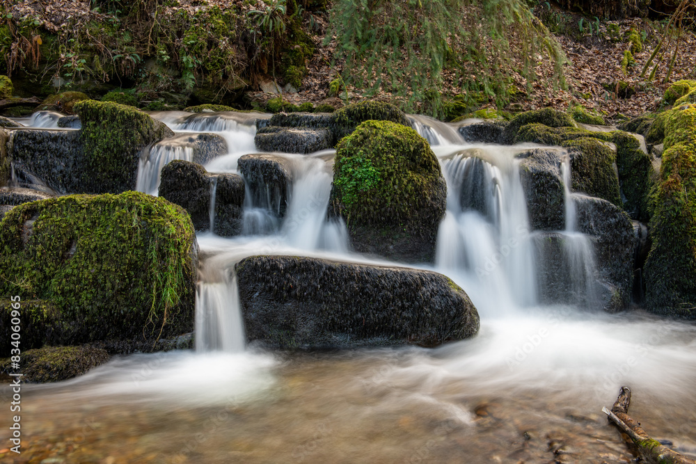 Long exposure of a waterfall flowing through the woods at Combe Park near Watersmeet in Exmoor National Park Long exposure of a waterfall flowing through the woods at Combe Park near Watersmeet in Exmoor National Park