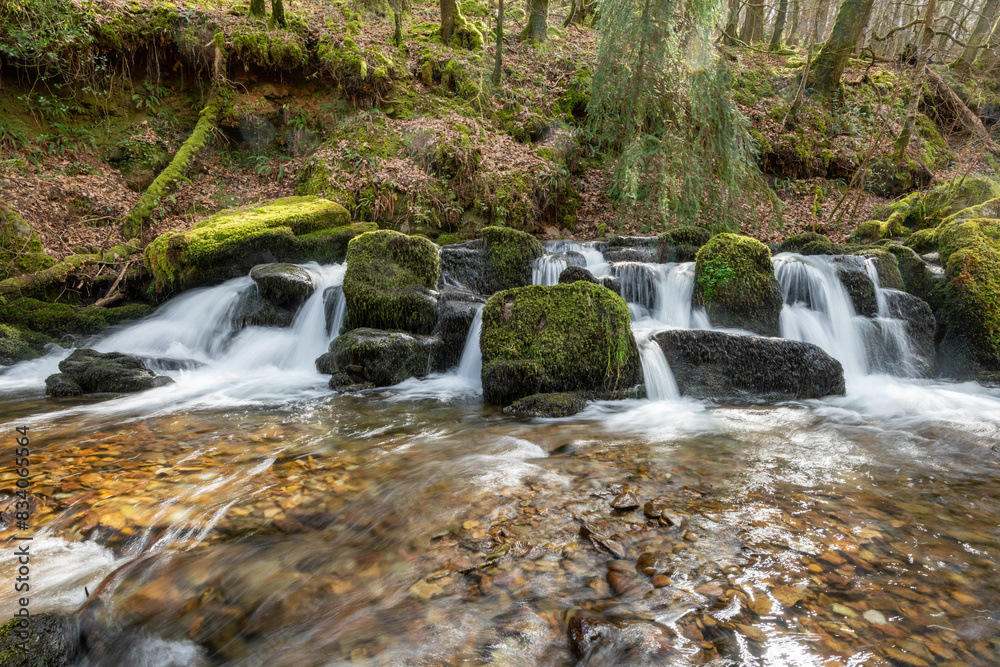 Fototapeta premium Long exposure of a waterfall flowing through the woods at Combe Park near Watersmeet in Exmoor National Park