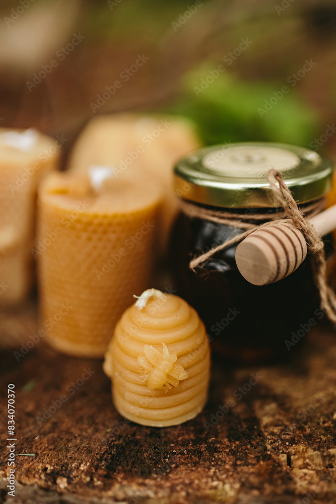 Handmade candles from natural beeswax in the shape of bear, pine cone and others, jars of honey. Hobby. Beekeeping. Artistic photo of beekeeping products against the backdrop of nature, forest