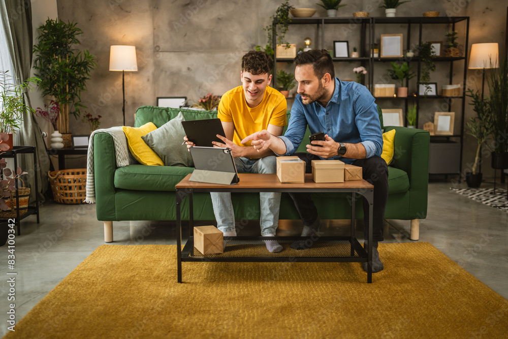 Two men check package delivery shipment status on tablet at home Two men check package delivery shipment status on tablet at home