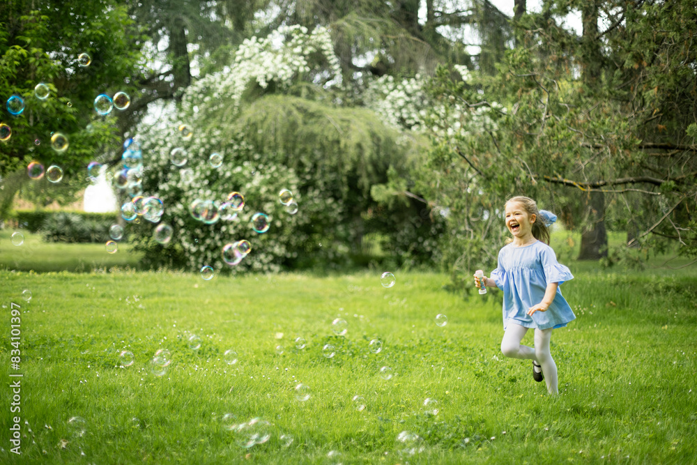 Joyful girl running through bubbles in a lush green park. Joyful girl running through bubbles in a lush green park.