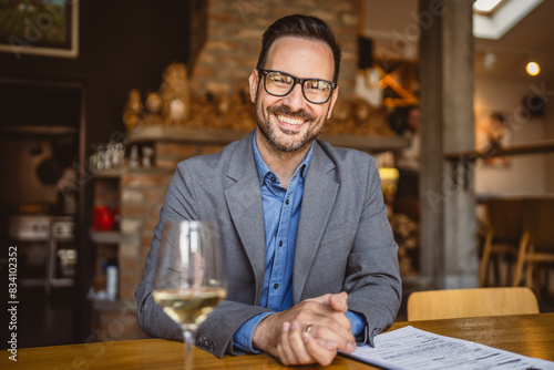 Adult man sit in a winery with glass of wine and clipboard