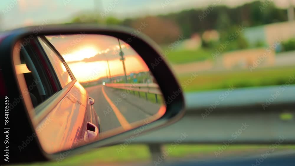 The sun is reflected in the mirror and window, evening road. View in the side rear view mirror of a car driving along the highway, in a red car The sun is reflected in the mirror and window, evening road. View in the side rear view mirror of a car driving along the highway, in a red car