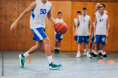 Cropped picture of junior athlete dribbling a basketball on training.