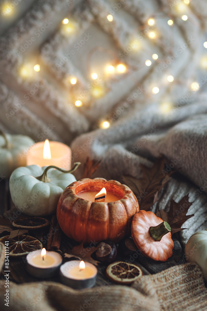 Atmospheric candle - shape of pumpkins, autumn decor on grey fall rainy day. Autumn cozy home atmosphere and inspiration, hygge concept. Aromatherapy, warming, relaxation. Wooden background