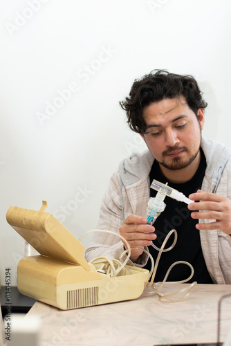 Person with respiratory problems in the living room trying to used a old nebulizer and get confused