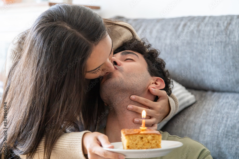 Woman kissing man on cheek while holding a birthday cake Woman kissing man on cheek while holding a birthday cake