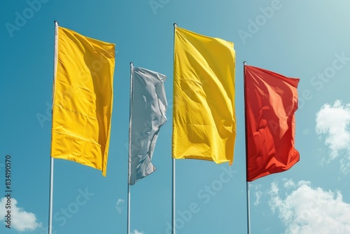 A group of four flags flying high in the sky, a bright blue sky with no clouds photo