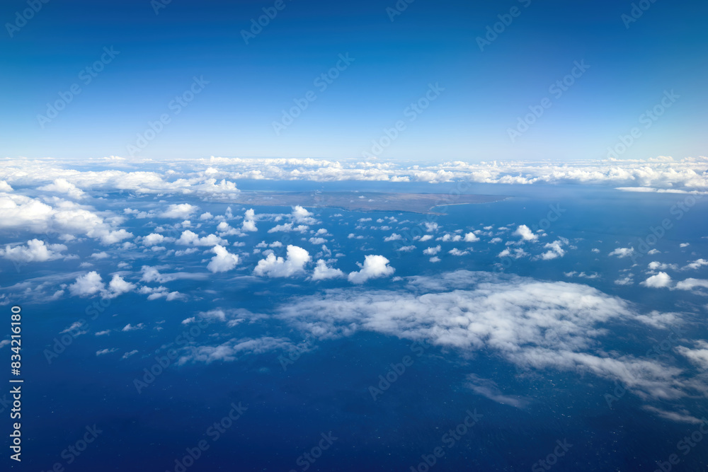 Aerial view of Hawaiian island of Molokai and its western coast against blue sky with clouds Aerial view of Hawaiian island of Molokai and its western coast against blue sky with clouds