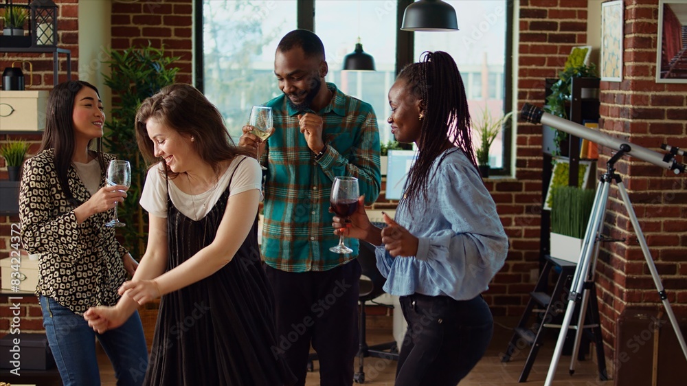 Obraz premium Diverse mix of guests at home party sharing laughter and dance moves in living room, dolly in shot. Friends dancing on disco beats during weekend hangout, shaking their shoulders
