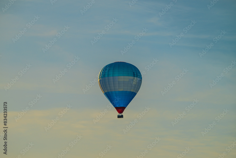 Obraz premium Blue white and red hot air balloon in evening sun.