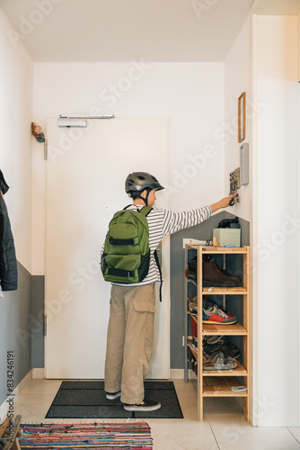 A girl with bicycle helmet and backpack picking up her keys to leave her house, morning routine