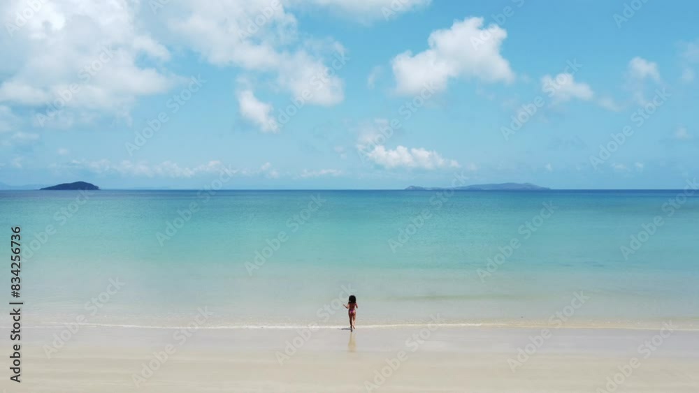 Aerial shot of a happy girl running towards the crystal clear water of the Australian coastline Aerial shot of a happy girl running towards the crystal clear water of the Australian coastline