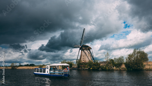 Dutch Windmills on Water with Storm Clouds, with Boat on Canal in Kinderdijk, The Netherlands