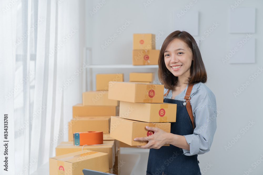 Delivery business. happy modern female checking order with laptop and using smartphone applications in the warehouse Delivery business. happy modern female checking order with laptop and using smartphone applications in the warehouse